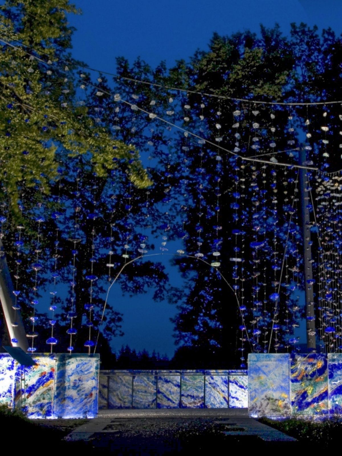 Karoli Waldkirchen bei Nacht mit leuchtender Installation zwischen den Bäumen.