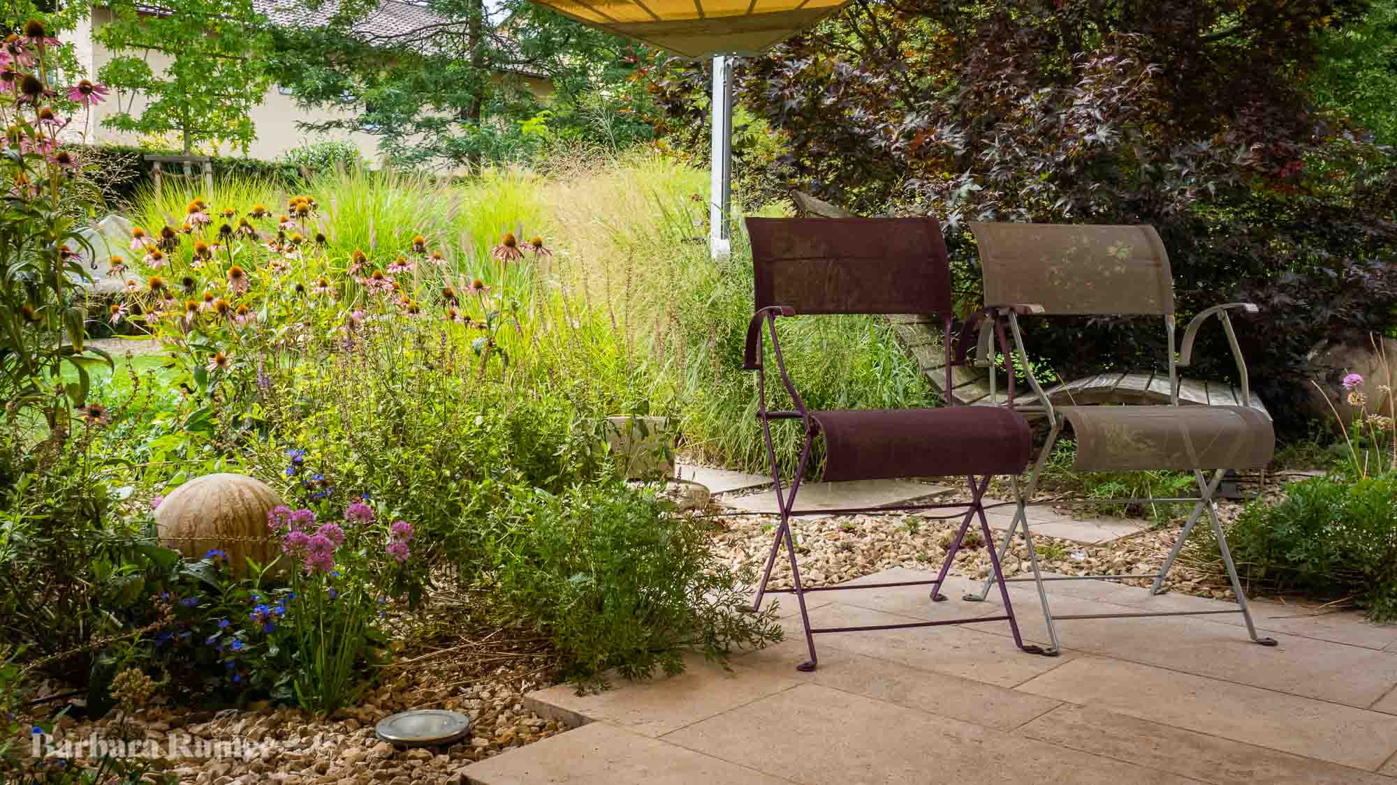 Wiederkehrende Pflanzen verbinden verschiedene Gartenräume zu einem harmonischen Ganzen.