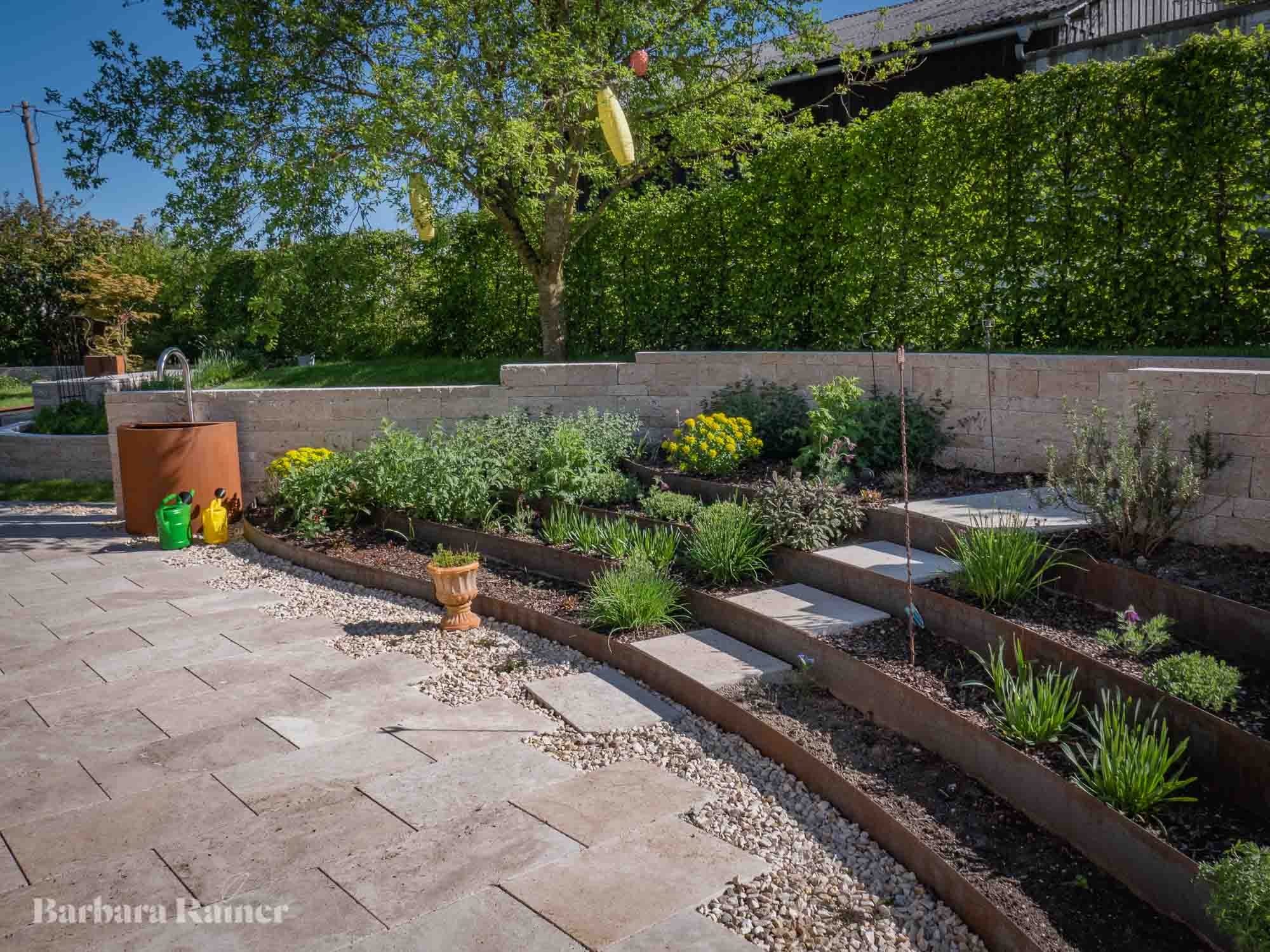 Stufen und Pflanzflächen verbinden Terrasse und Garten