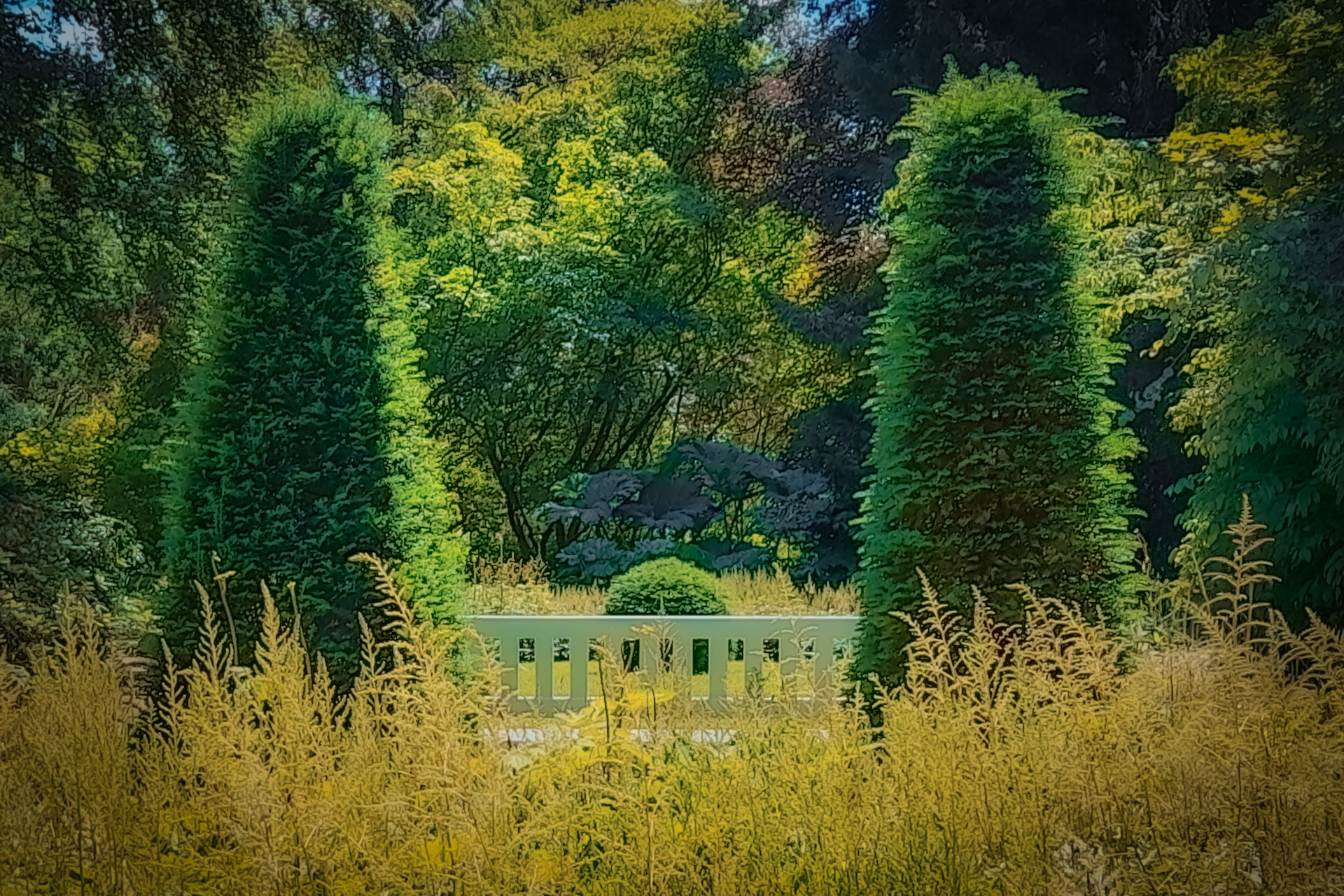 Blick durch hohe Gräser auf eine Gartenarchitektur zwischen Bäumen